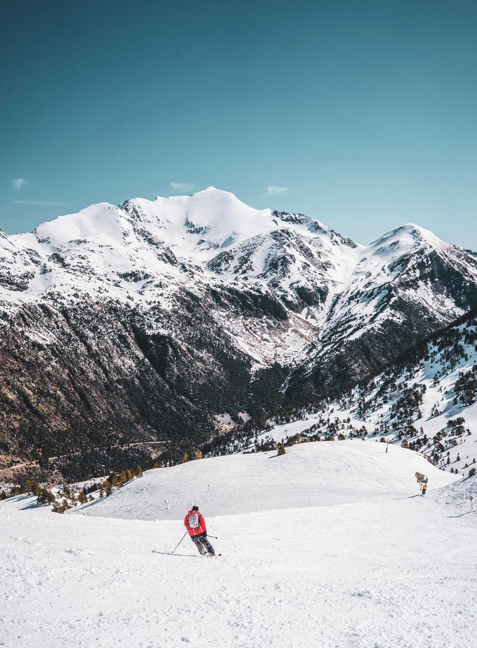 A skier on a groomed slope below the snowy Pyrenees peaks, Andorra