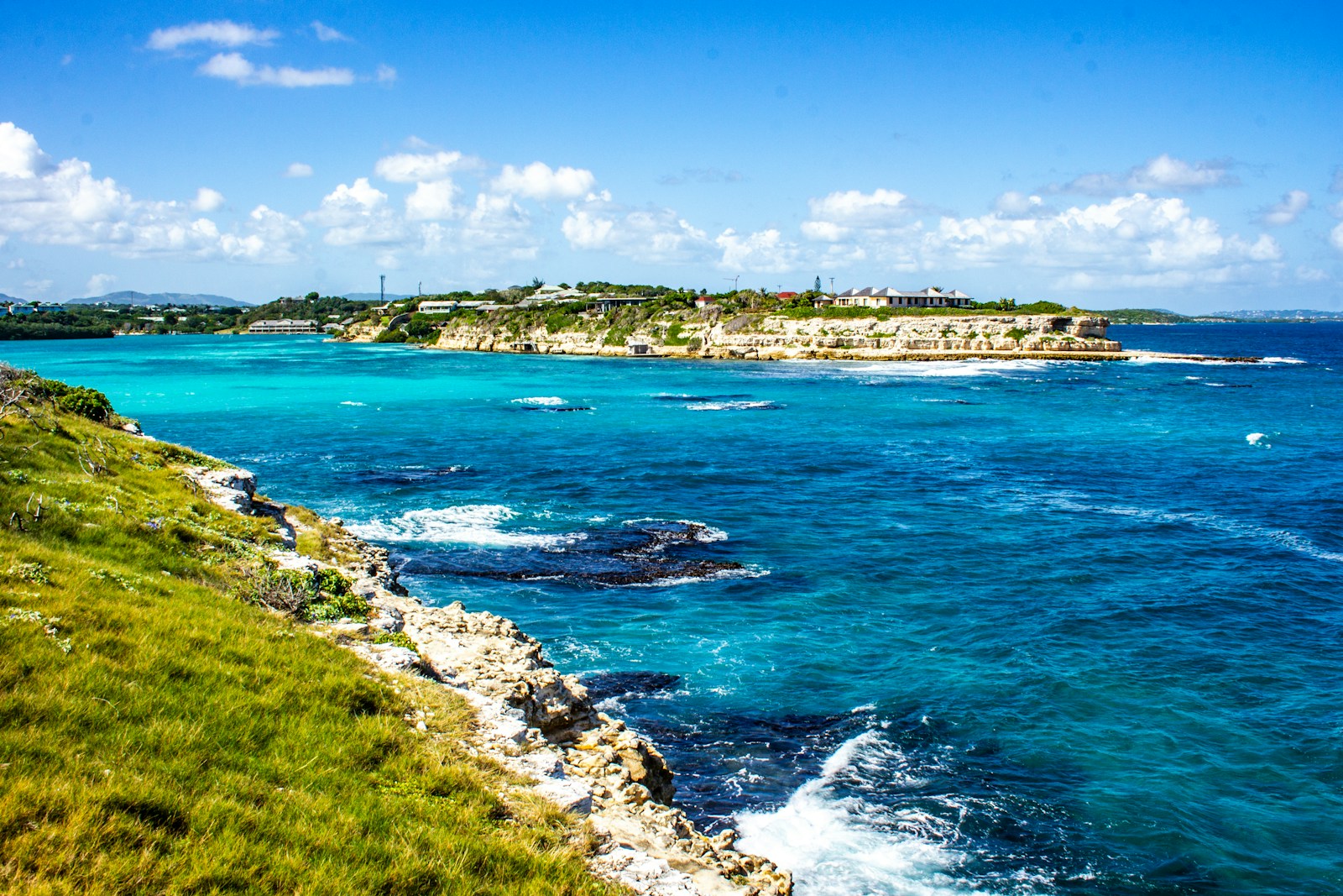 A turquoise cliff coast with reef and a green headland, Antigua