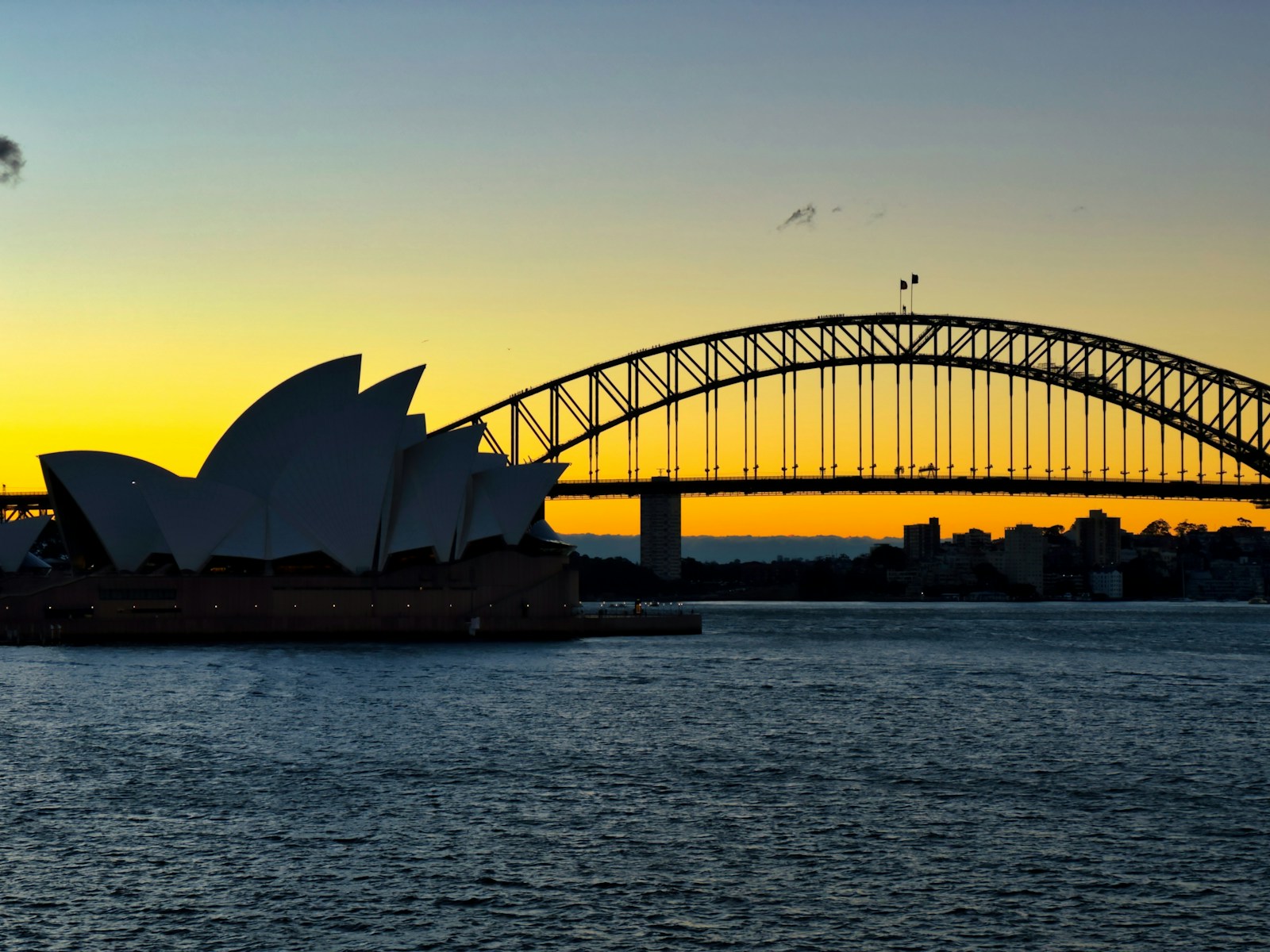 The Sydney Opera House and Harbour Bridge silhouetted against a golden sunset