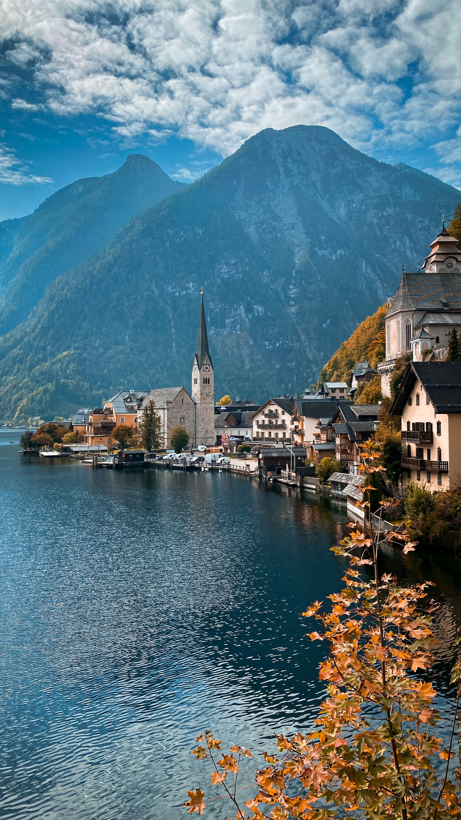 The church spire and lakeside houses of Hallstatt reflected in the lake below alpine peaks