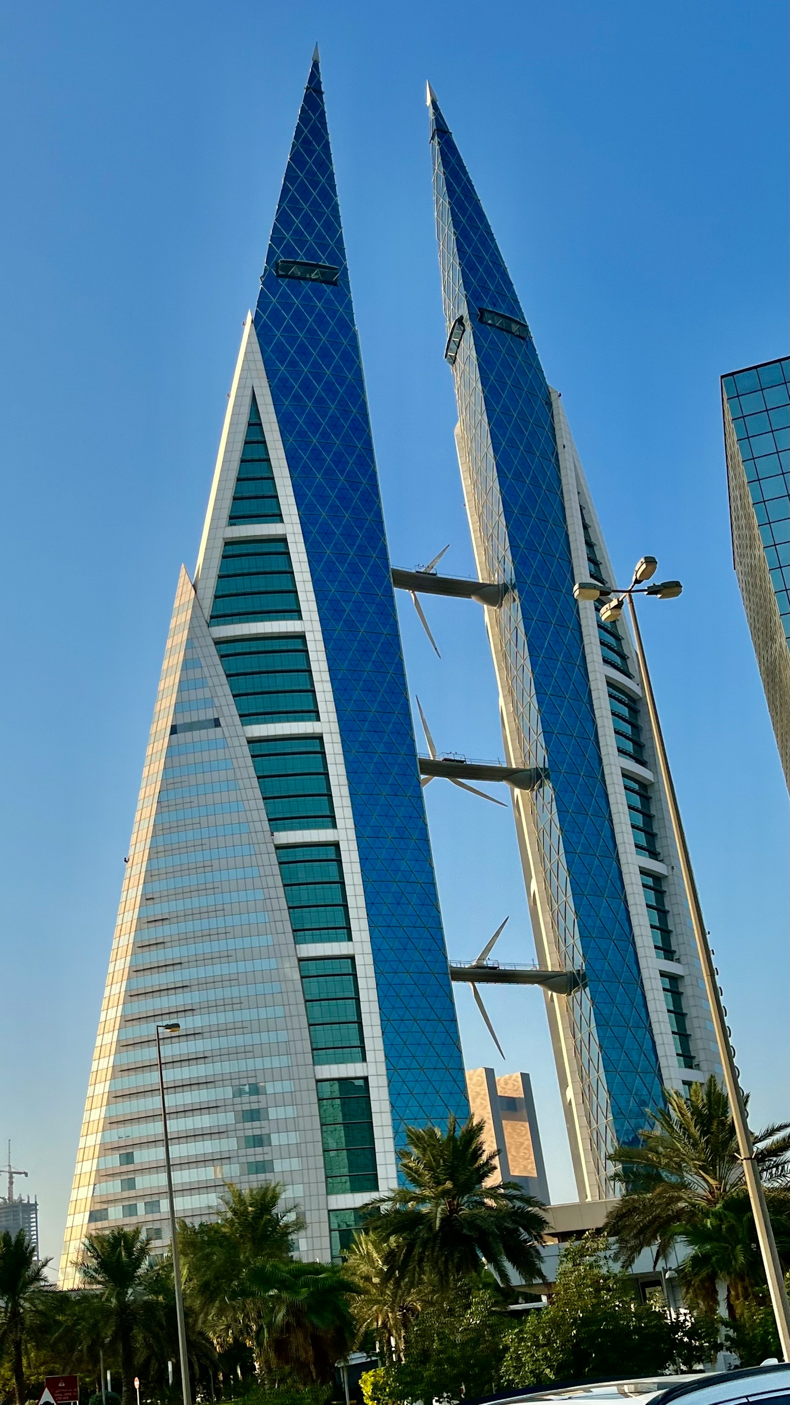 The twin sail-shaped towers of the Bahrain World Trade Center with wind turbines between them, Manama