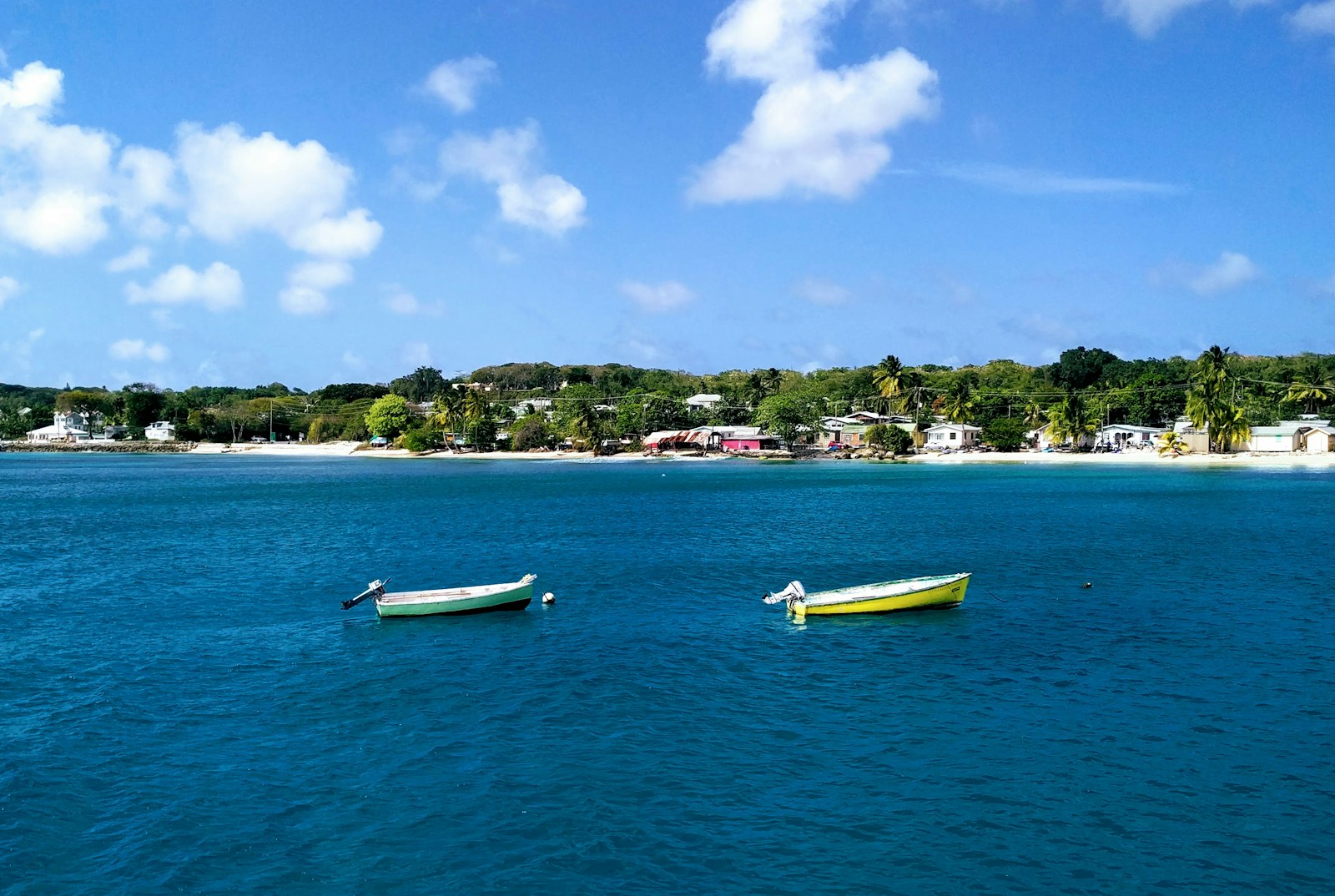 Two small fishing boats on a calm turquoise bay off a Barbados village