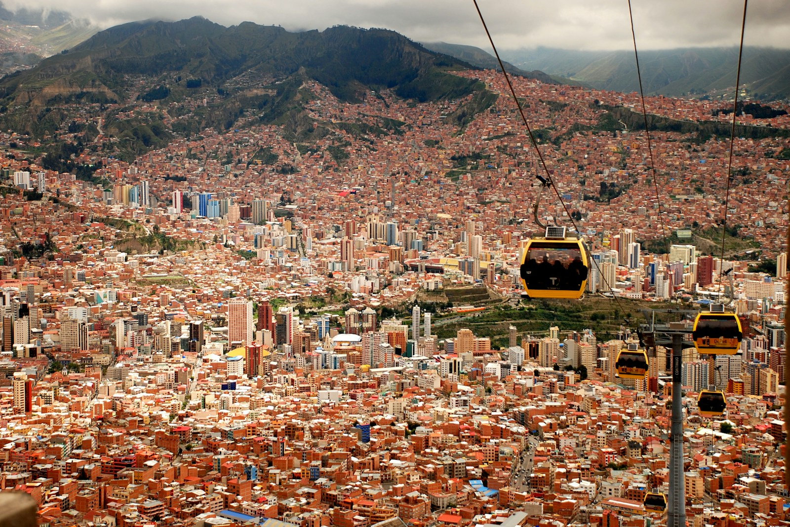 Yellow Mi Teleferico cable cars gliding over the brick-red canyon city of La Paz, Bolivia