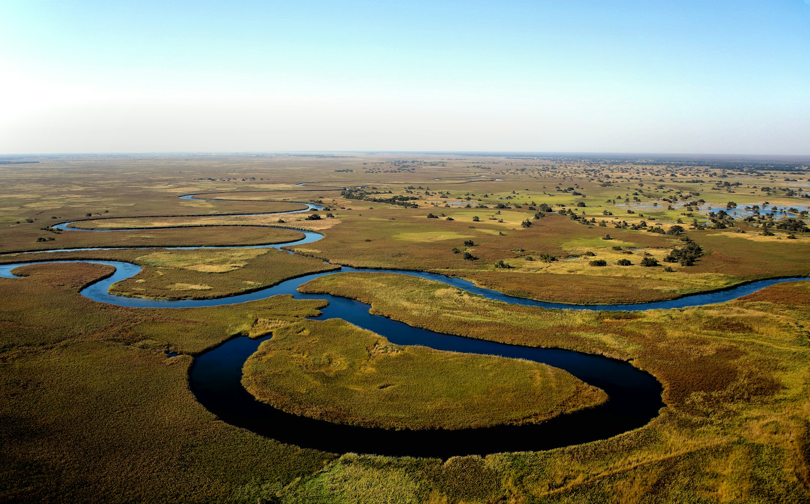 An aerial view of the winding blue channels and green floodplains of the Okavango Delta in Botswana
