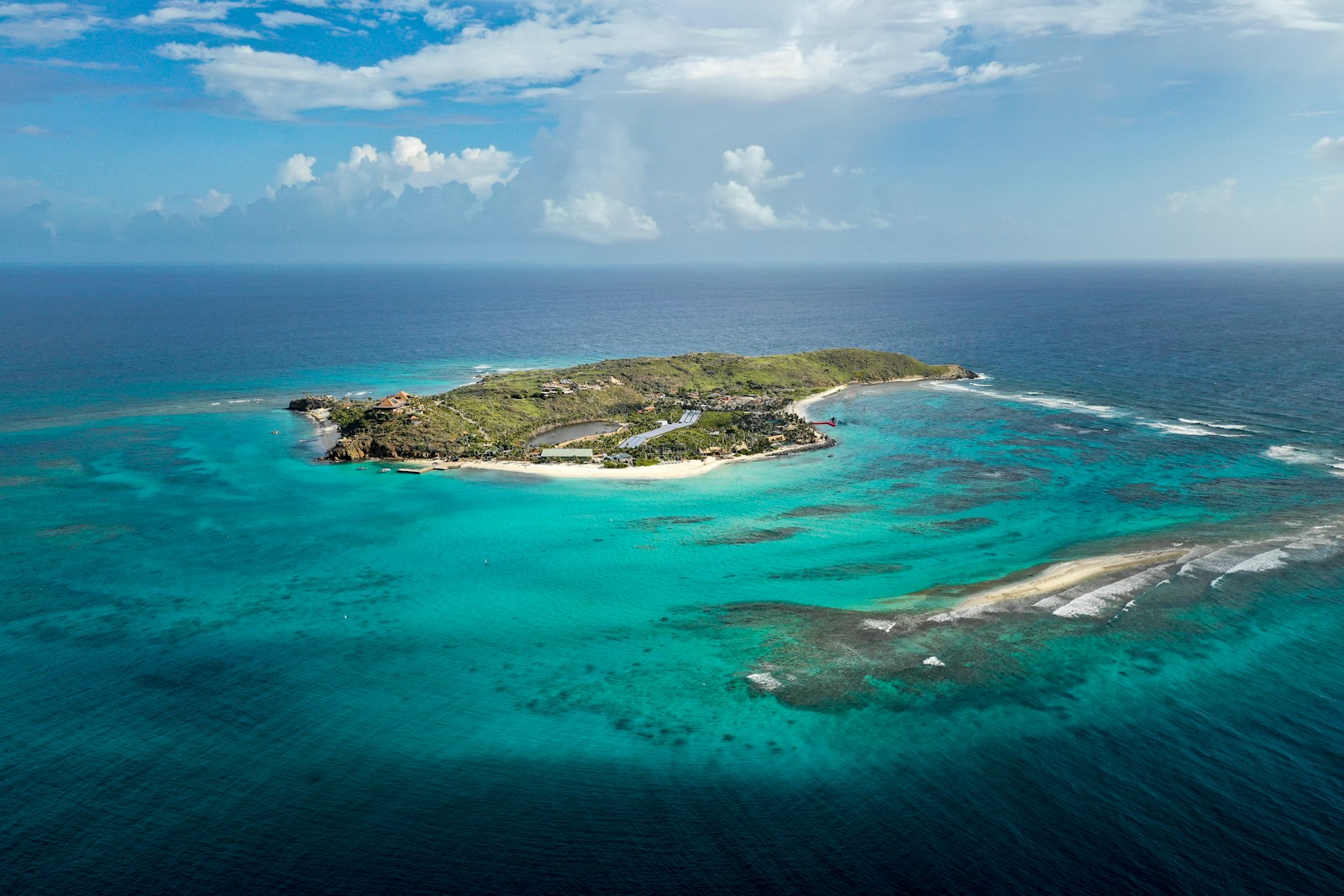 An aerial view of a small green island ringed by turquoise reef, British Virgin Islands