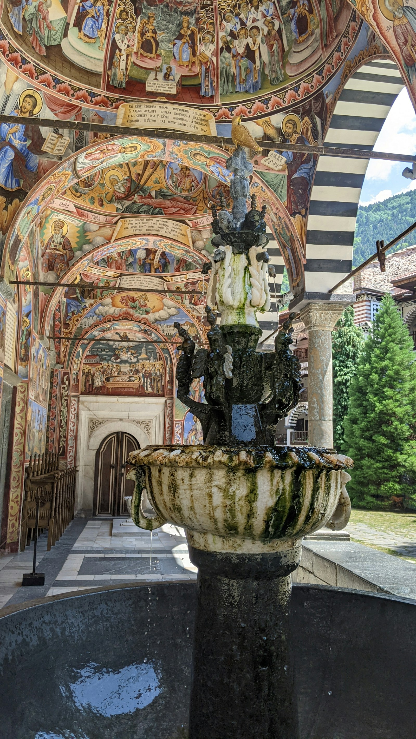 The vividly frescoed striped arcades and fountain of the Rila Monastery in Bulgaria