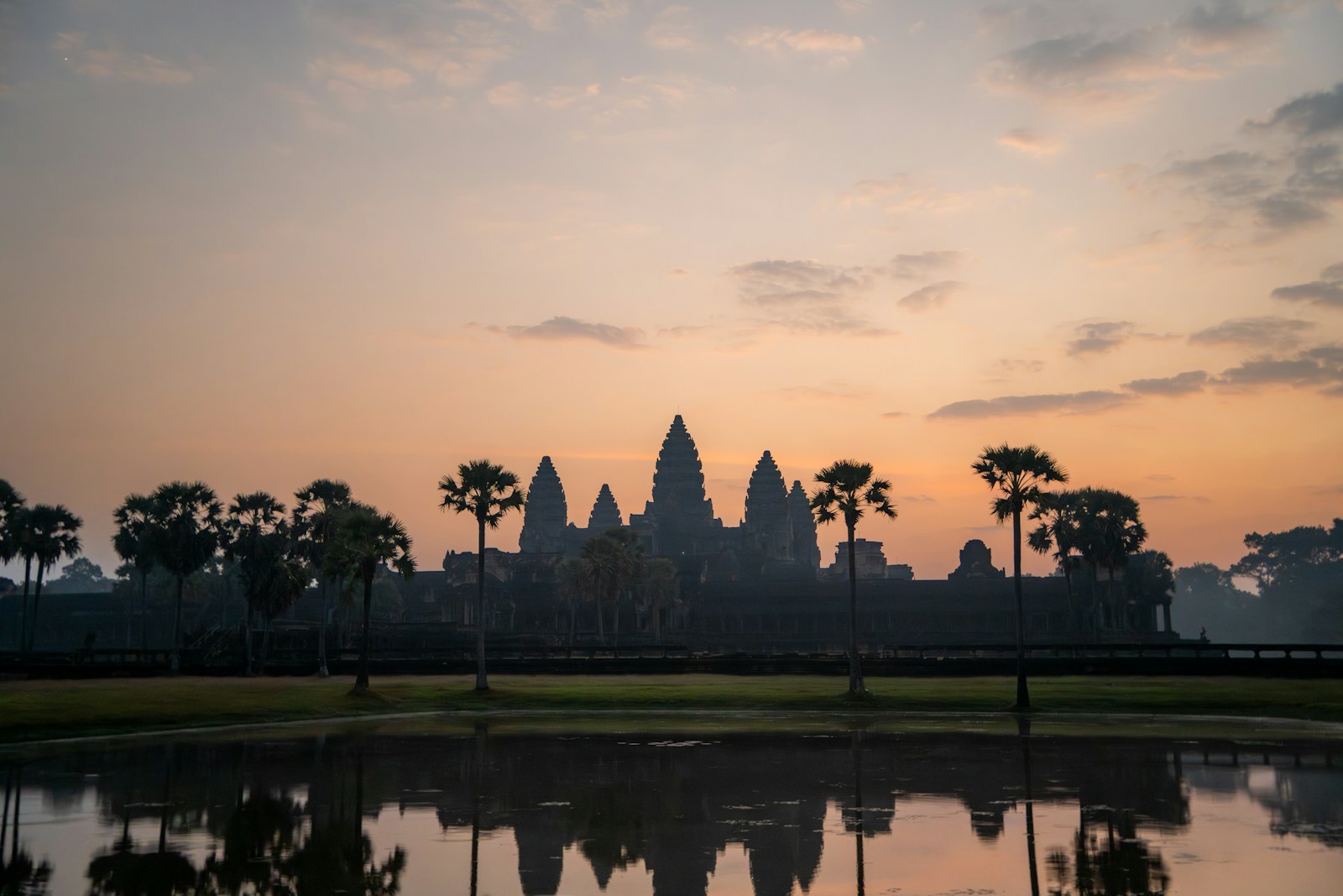 The towers of Angkor Wat silhouetted at sunrise, reflected in the pool