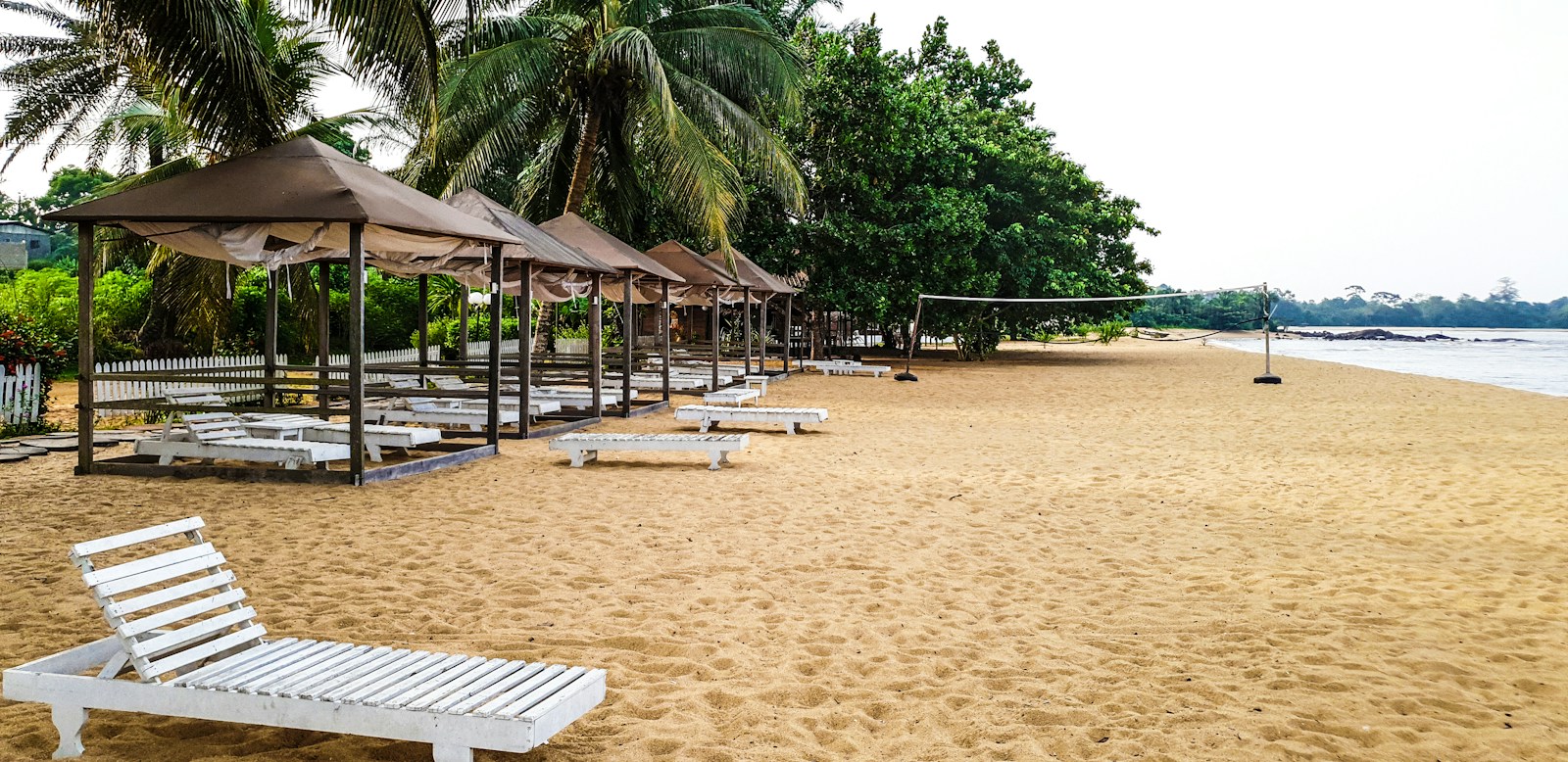 Palm-shaded loungers and cabanas on the sand at Kribi beach, Cameroon