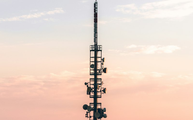 A phone mast against a pink sunset sky