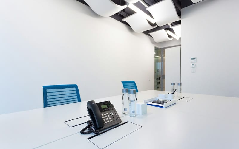 An IP desk phone on a white meeting table in a bright office