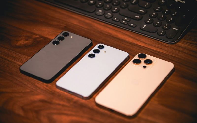 Three smartphones side by side on a wooden desk