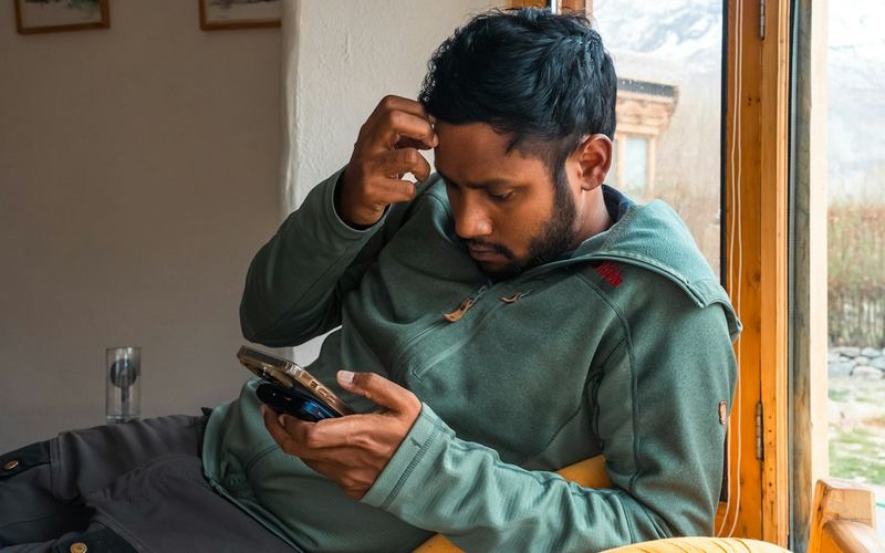 A puzzled man looking at his phone
