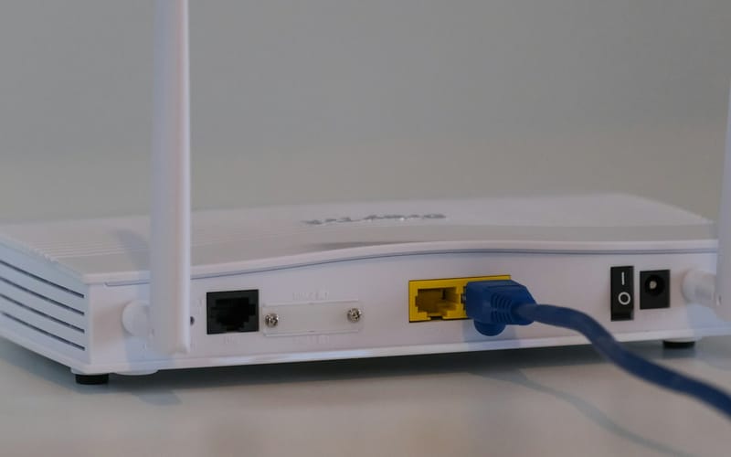 A white Wi-Fi router with a blue network cable plugged in