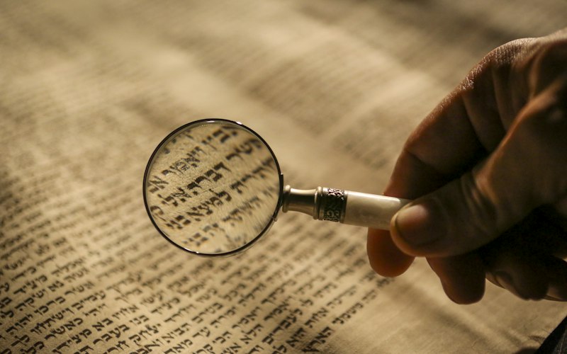 A hand holding a magnifying glass over printed text
