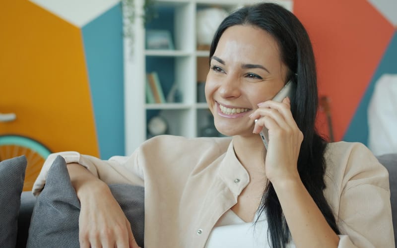 A woman smiling on a phone call on her sofa