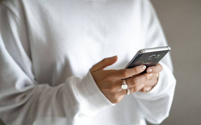 A person in a white sweater using a phone