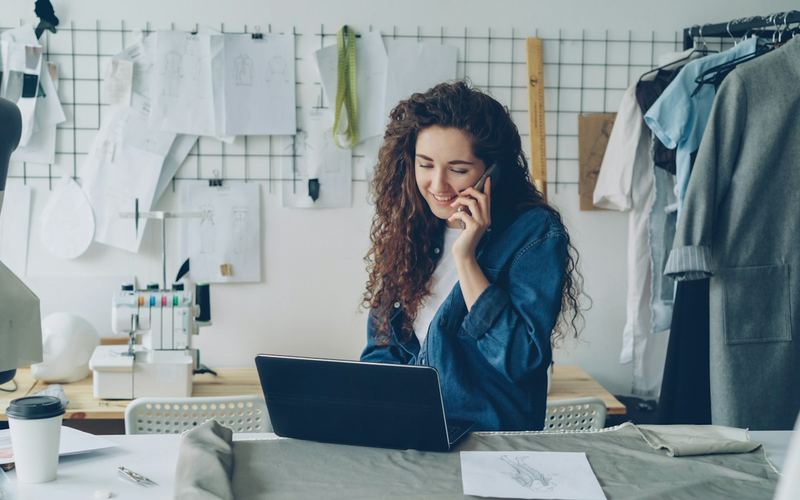 A designer smiling on a phone call at her desk
