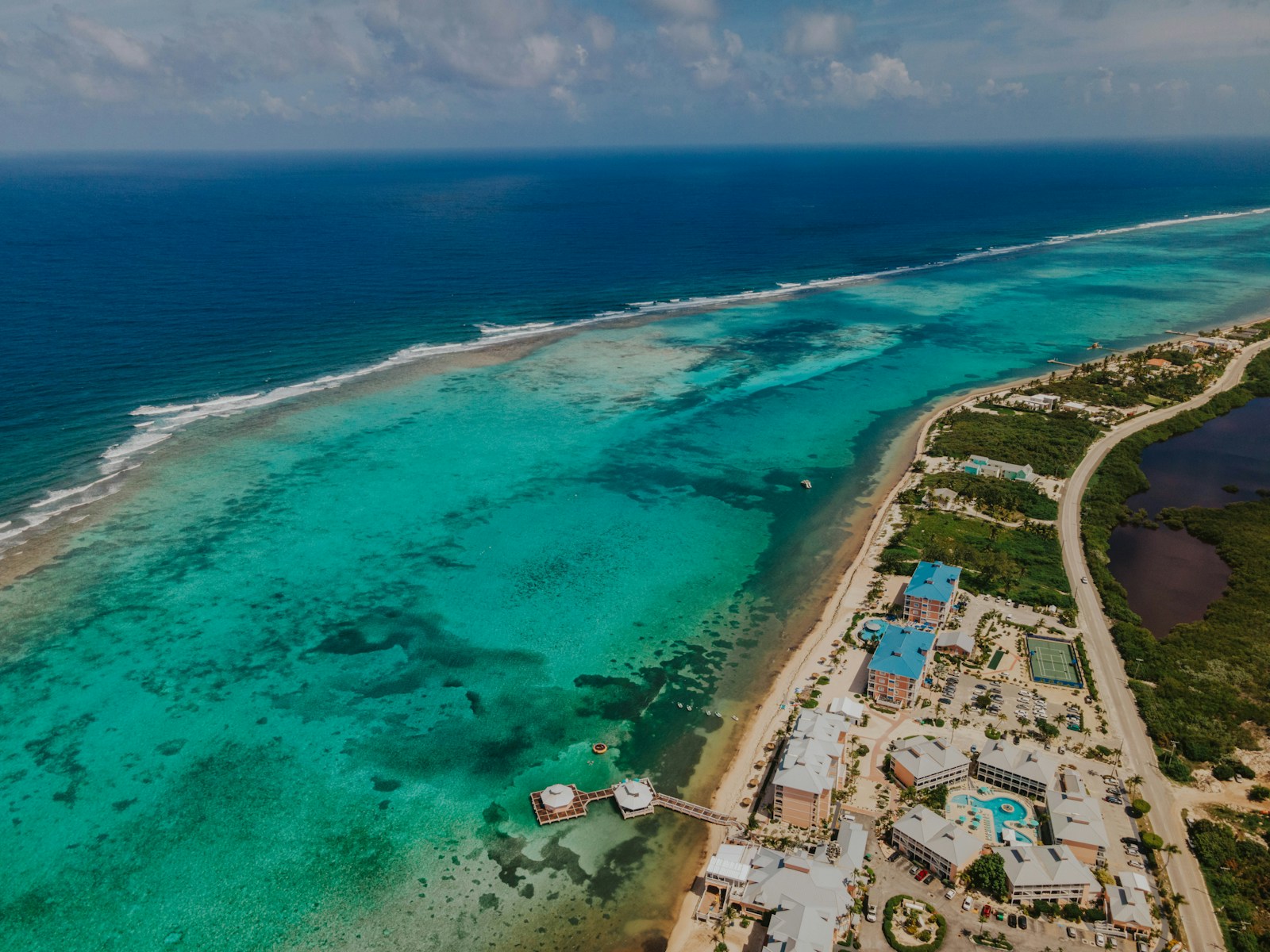 An aerial view of the turquoise reef coast with resorts, Grand Cayman