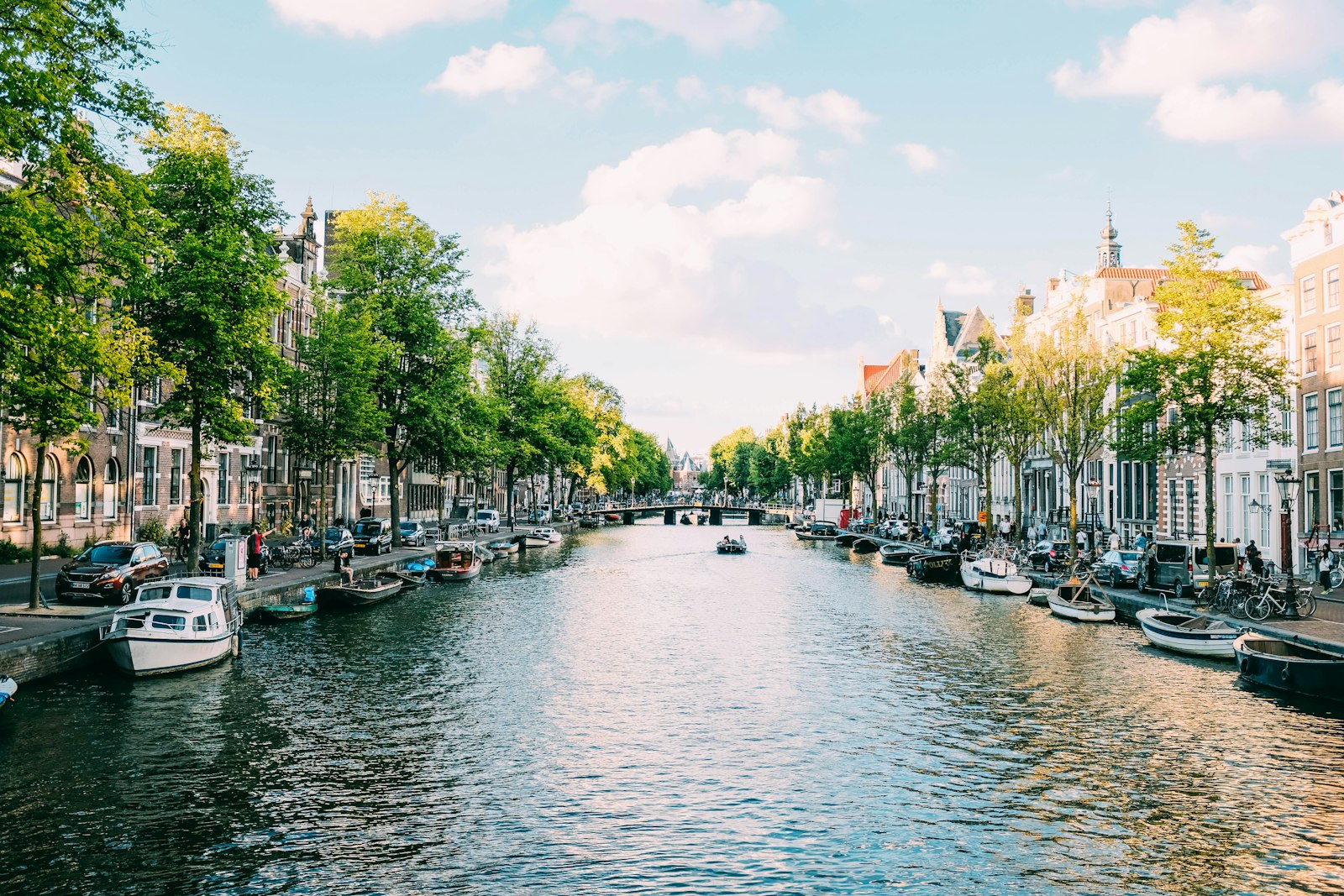 Boats on a tree-lined canal with historic houses in Amsterdam