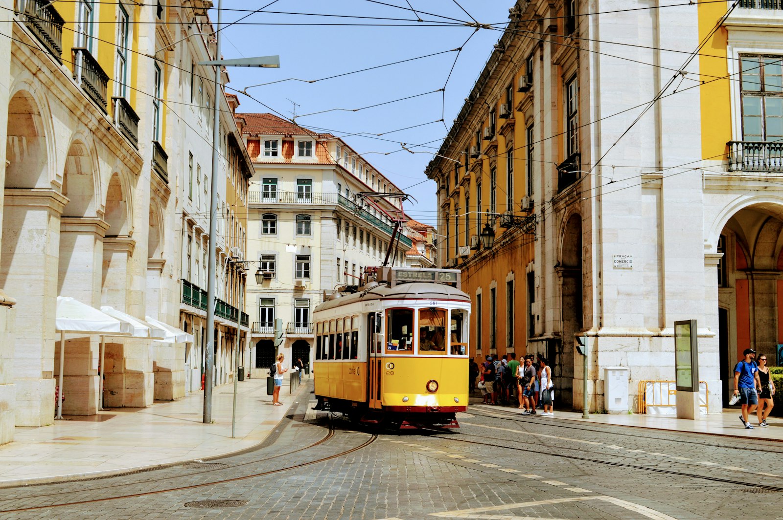 A yellow tram on a historic street in Lisbon, Portugal