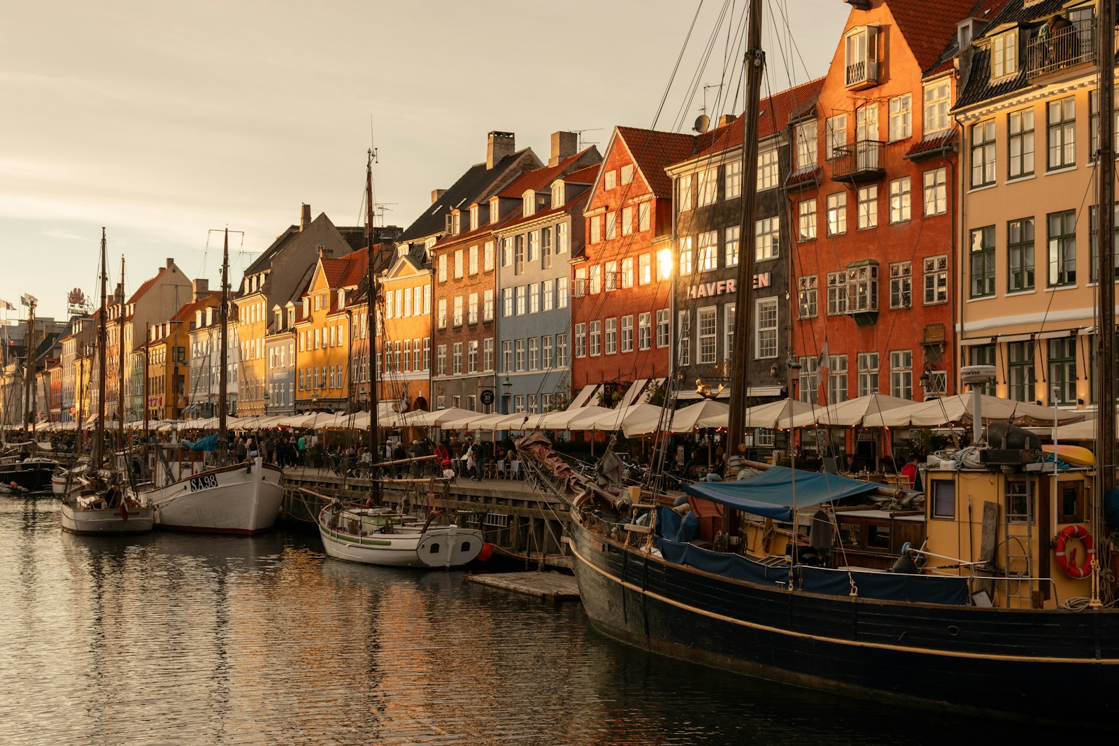 The colourful townhouses and old wooden boats of Nyhavn harbour in Copenhagen at golden hour