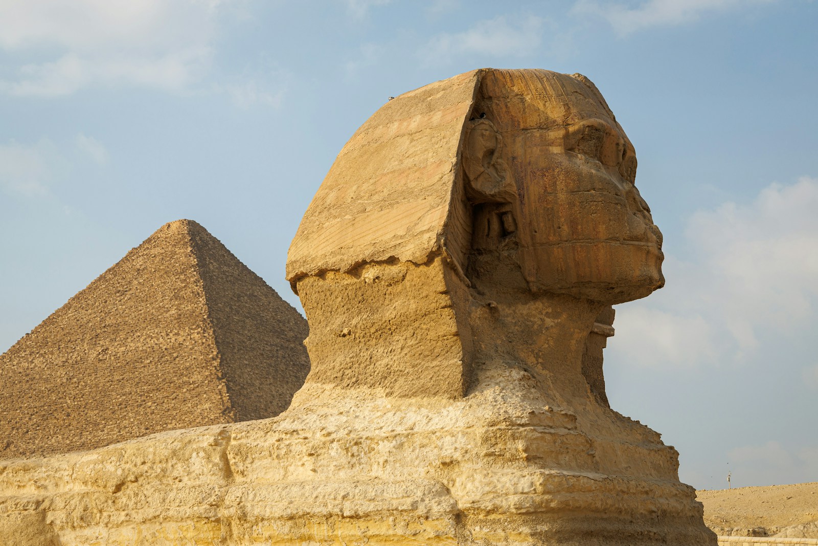 The Great Sphinx with a pyramid of Giza rising behind it