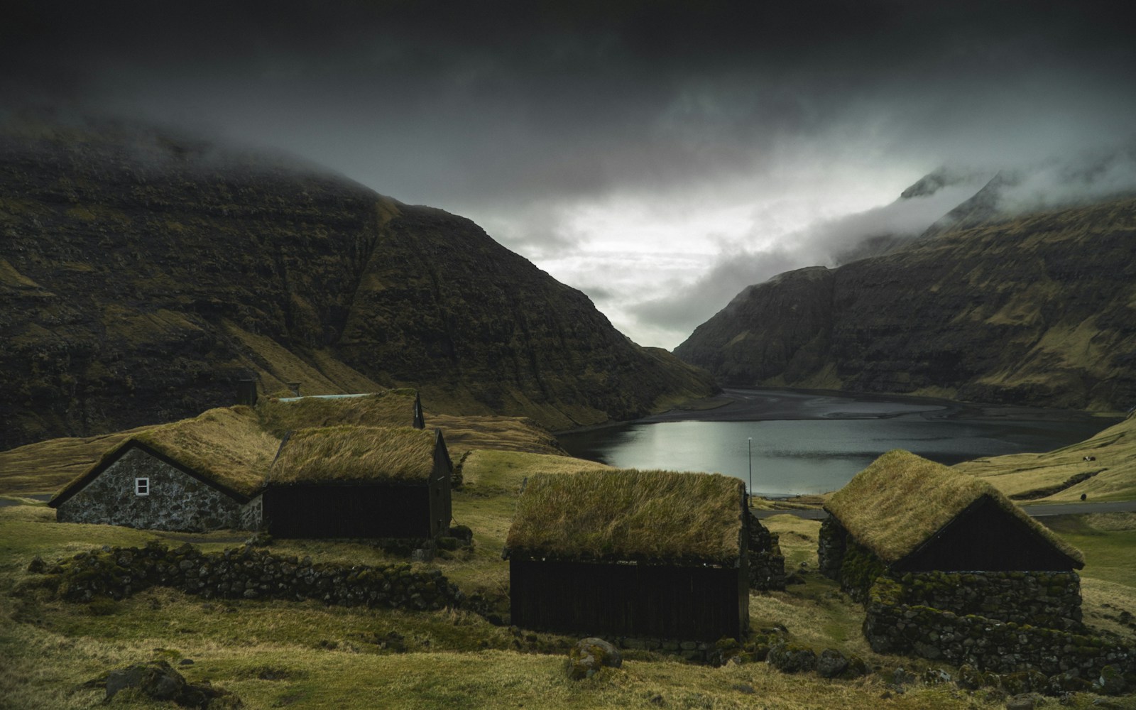 Turf-roofed stone houses at Saksun below moody mountains, Faroe Islands