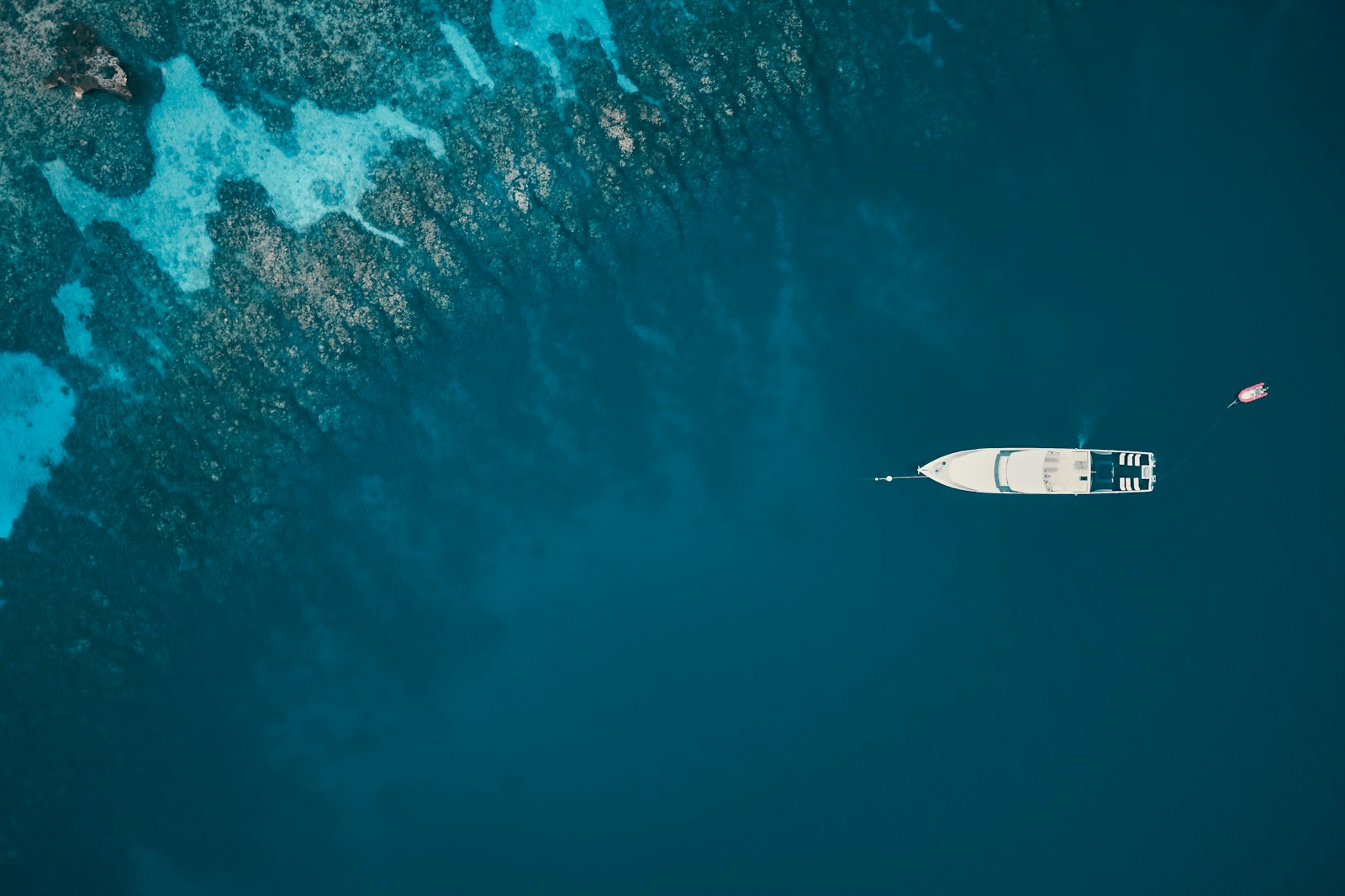 An aerial view of a dive boat moored over the turquoise reef shelf off Roatan, Honduras