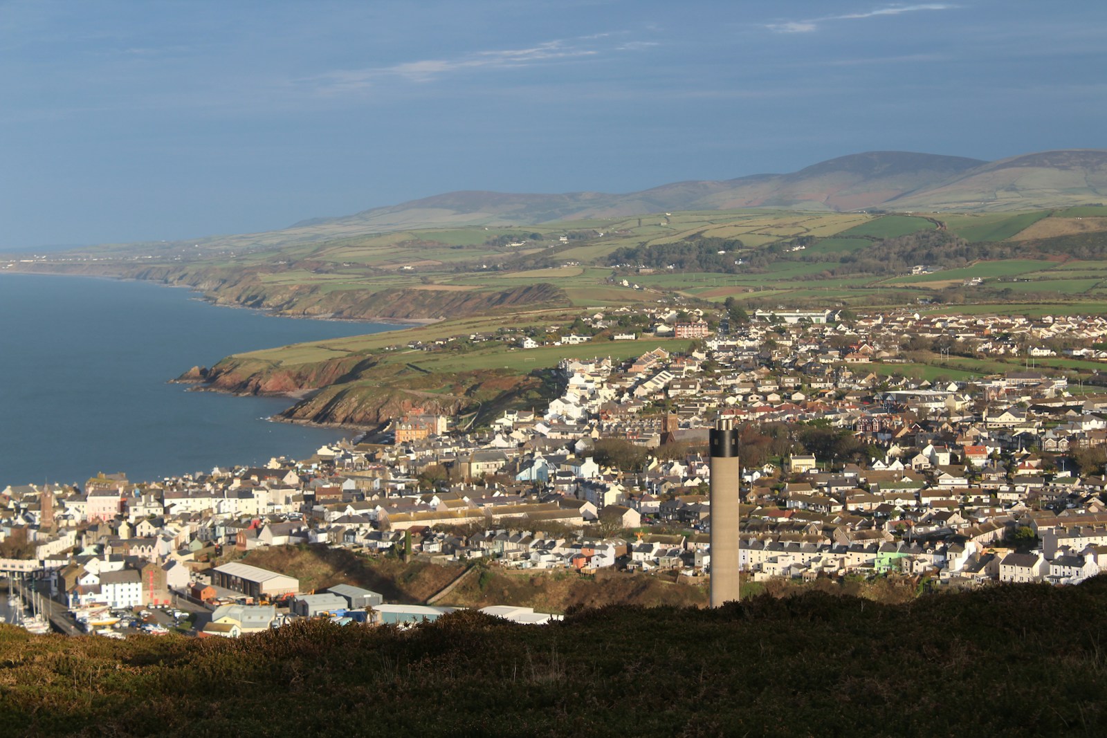 A Manx coastal town below green hills and the Irish Sea, Isle of Man