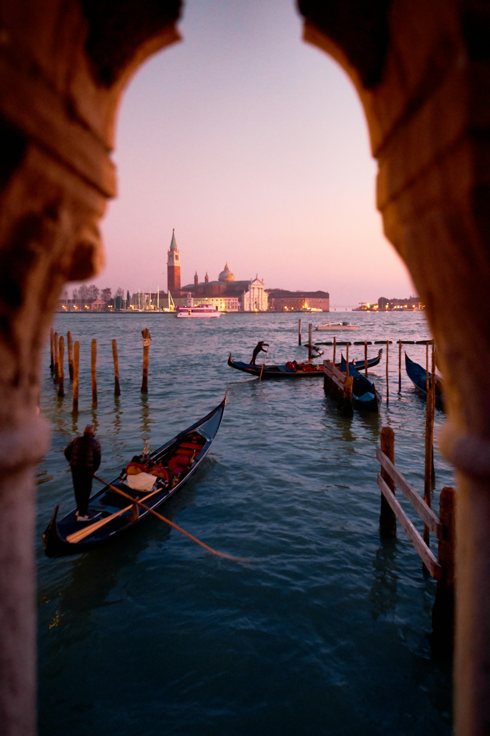 Gondolas moored at dusk in Venice, framed by an archway