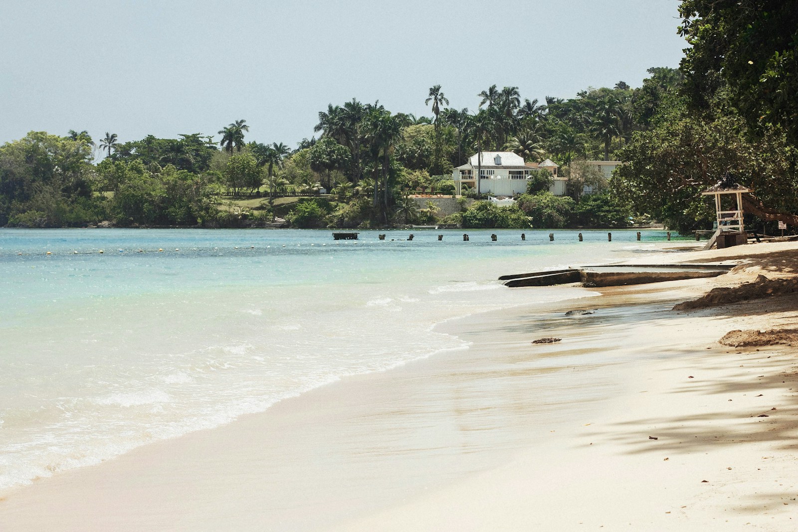 A quiet turquoise cove fringed with palms and a colonial house on Jamaica's north coast