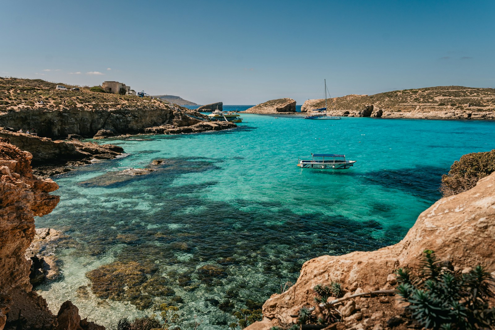 The turquoise water of the Blue Lagoon at Comino, Malta, with boats and rocky coast