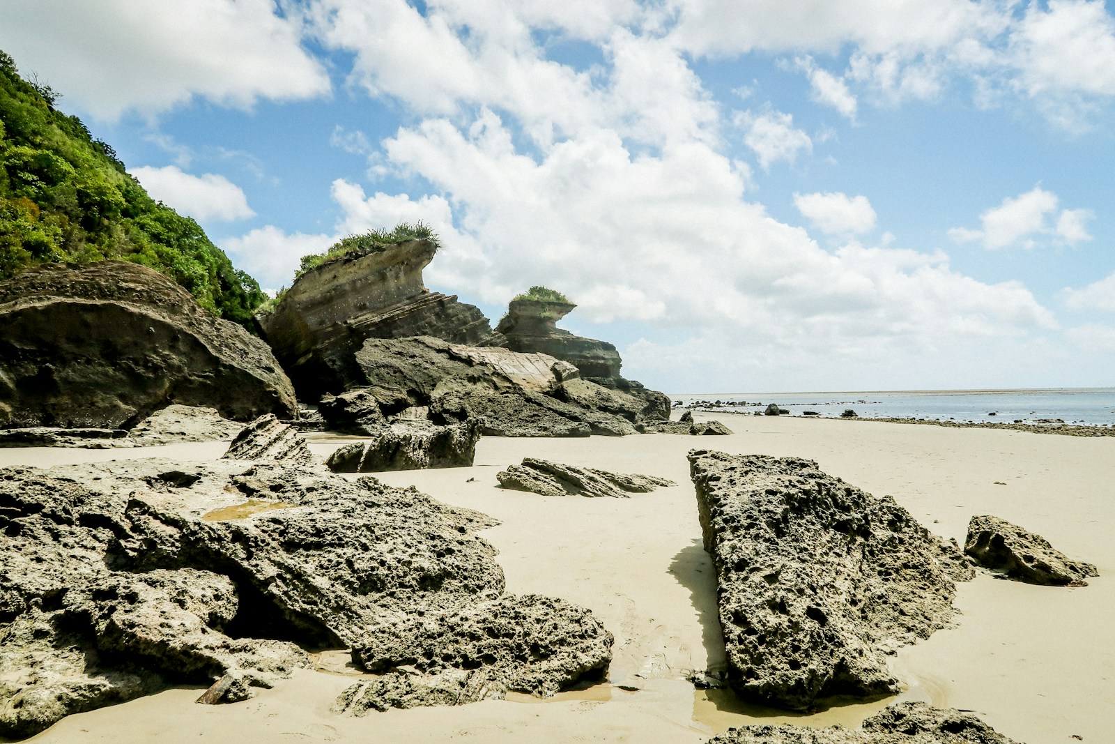 Weathered coral rock formations on a wide low-tide beach, Mayotte