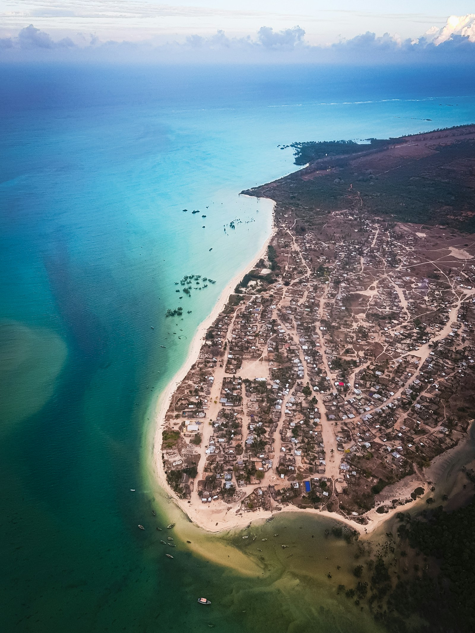 An aerial view of a Mozambican coastal village on a sandy spit by the turquoise Indian Ocean