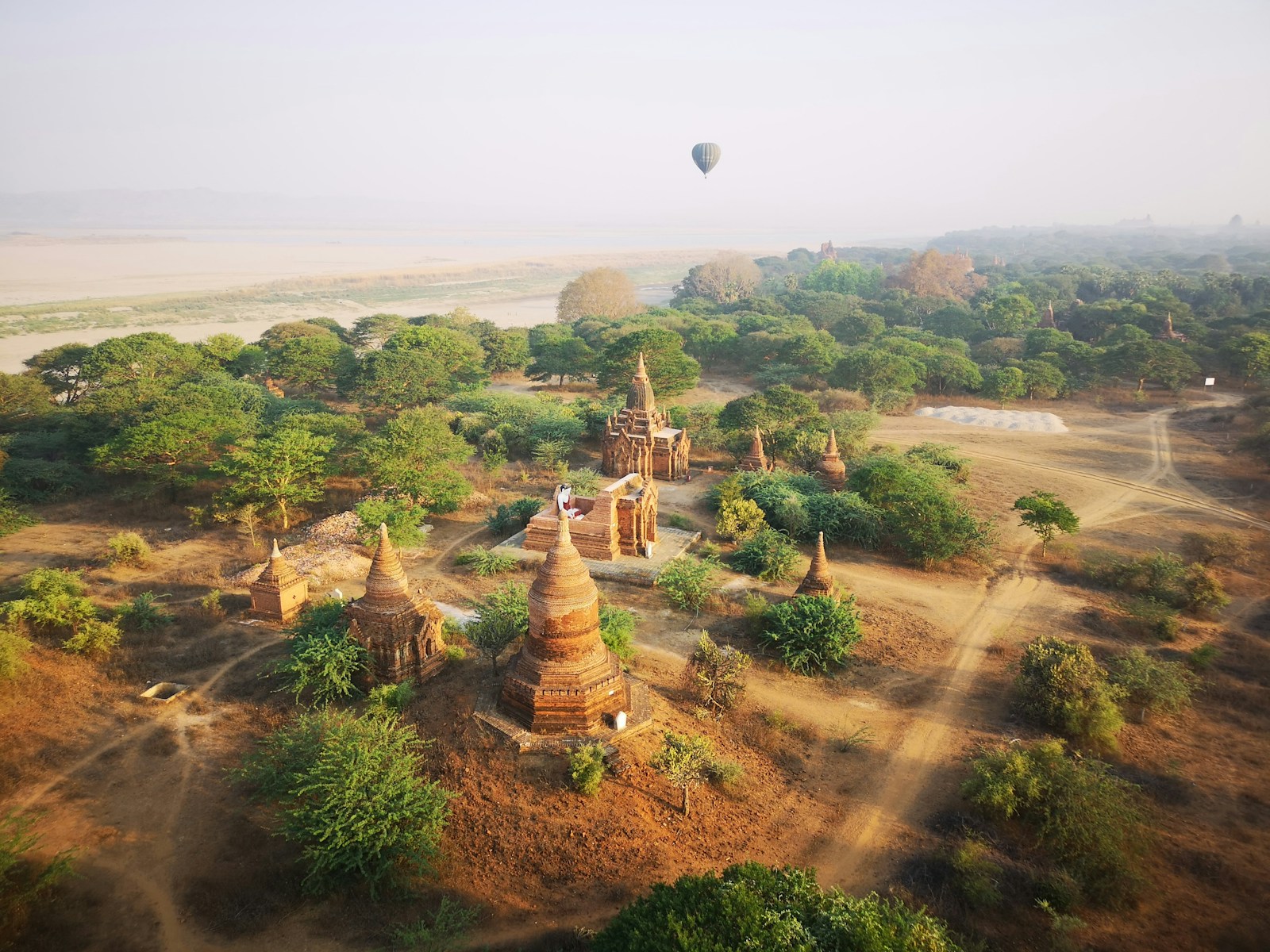 The temple plain of Bagan at dawn with a hot-air balloon aloft over the stupas, Myanmar