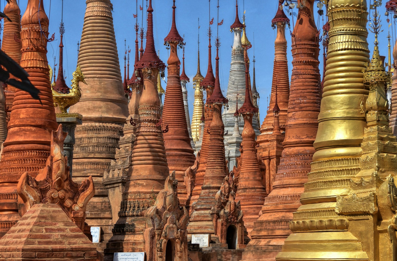 A dense cluster of ornate red-and-gold pagoda spires, Myanmar