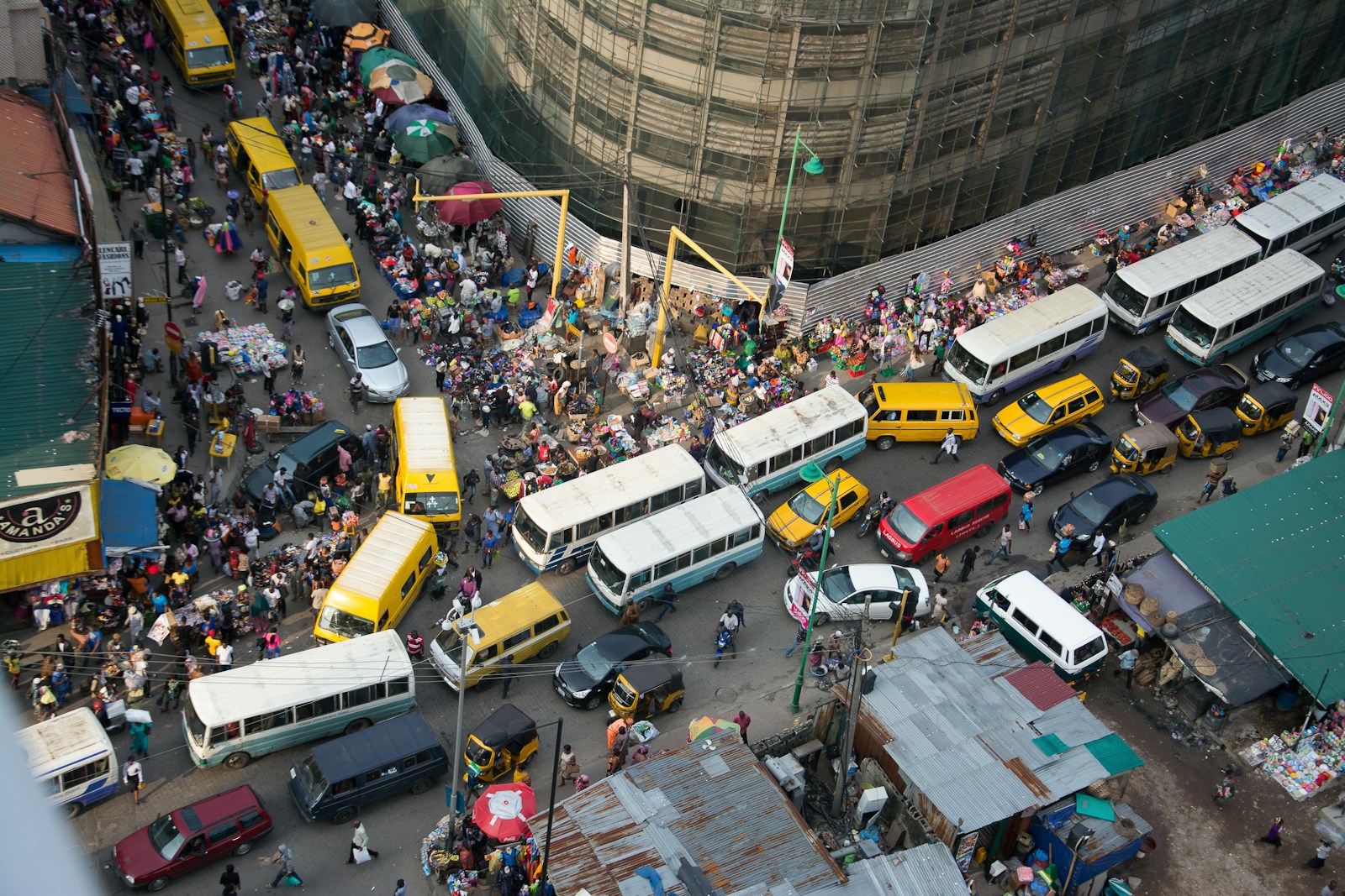 A packed Lagos Island street of yellow danfo buses, market stalls, and crowds in Nigeria