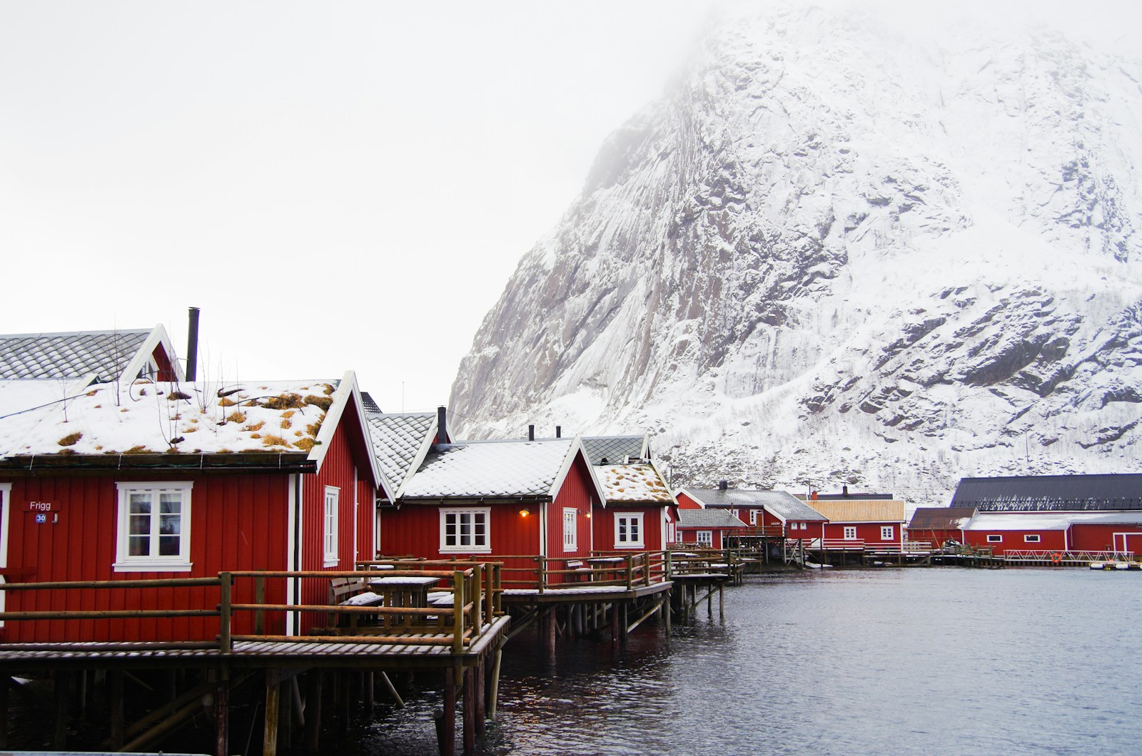 Red rorbu fishing cabins below a snowy peak in the Lofoten islands