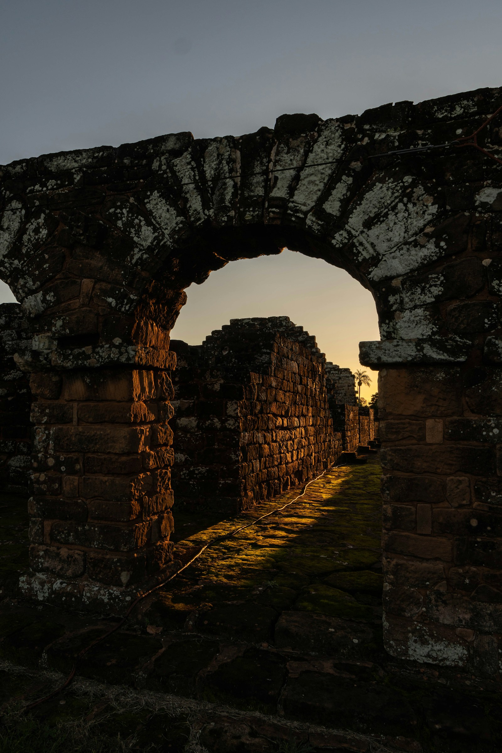 A moss-covered stone arch of the Jesuit mission ruins glowing at sunset, Paraguay