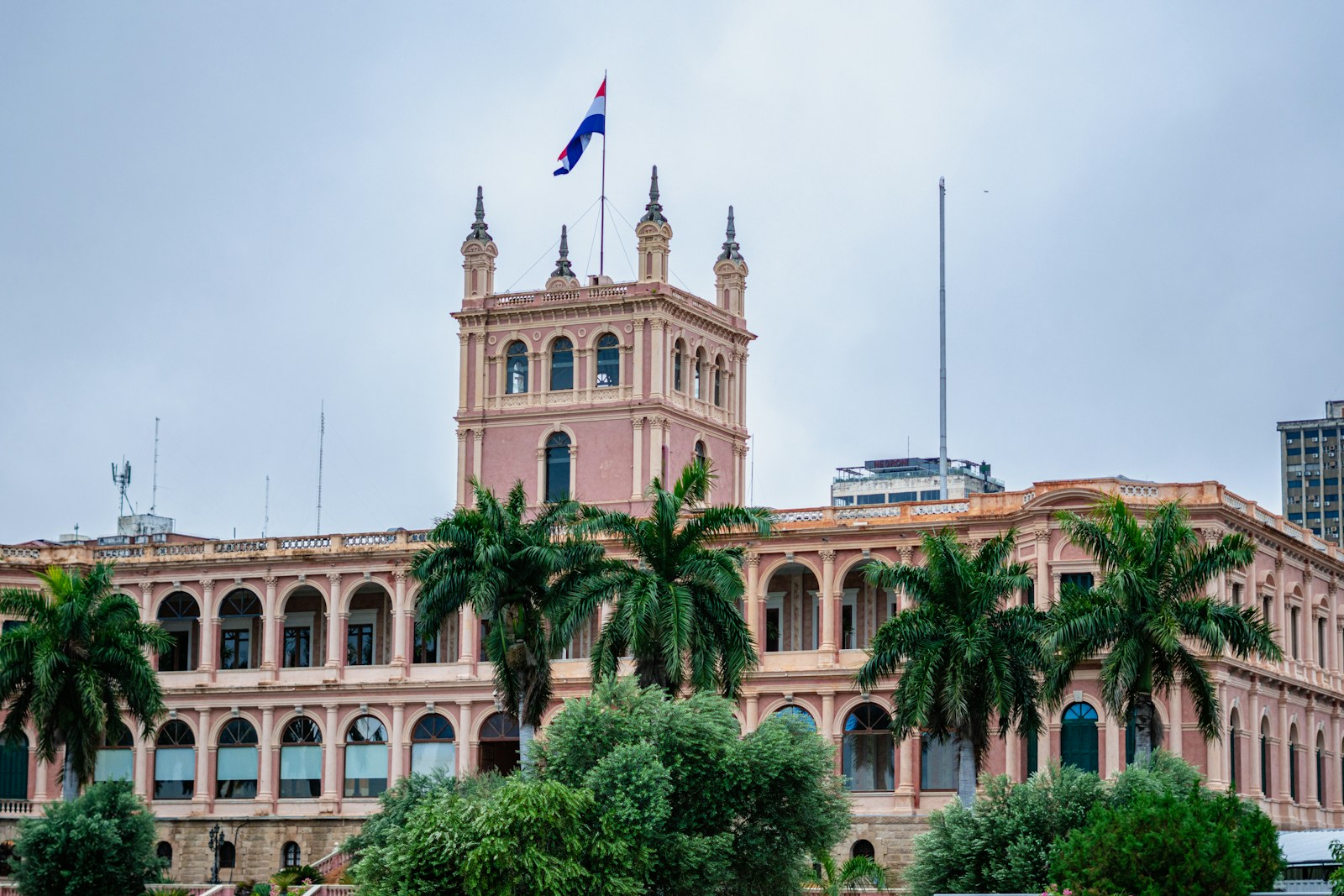 The pink Palacio de los Lopez presidential palace with the Paraguayan flag and palm trees, Asuncion