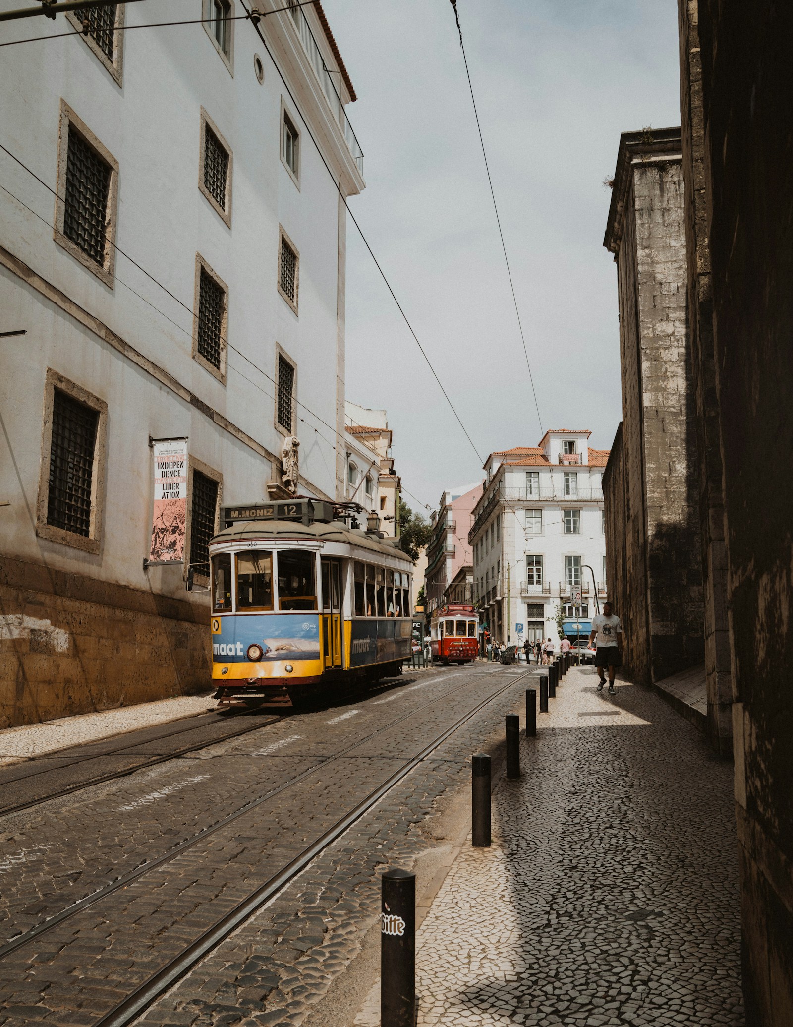 The yellow Tram 28 climbing a cobbled street in the Alfama, Lisbon