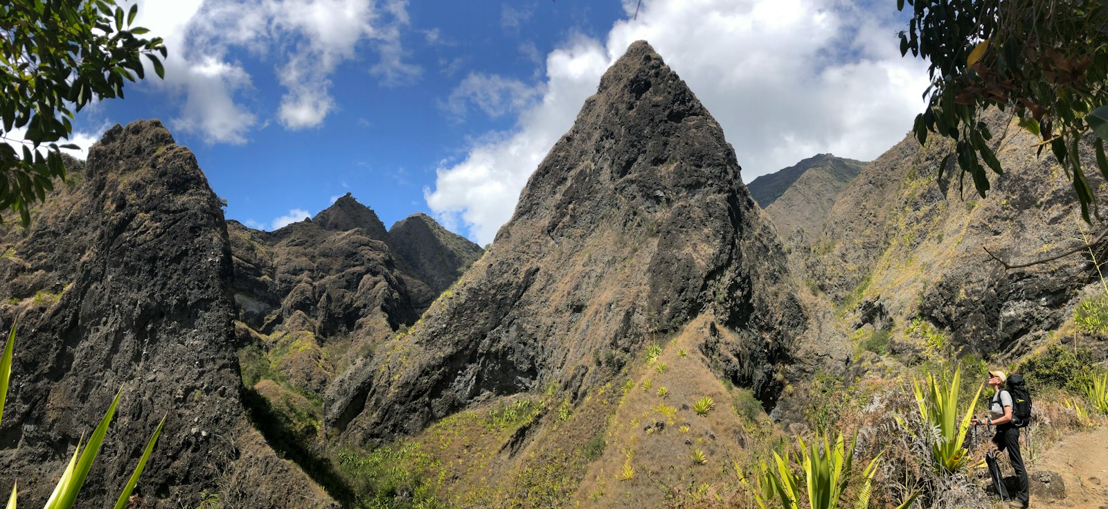 Jagged volcanic pinnacles above a hiker on a mountain trail, Reunion