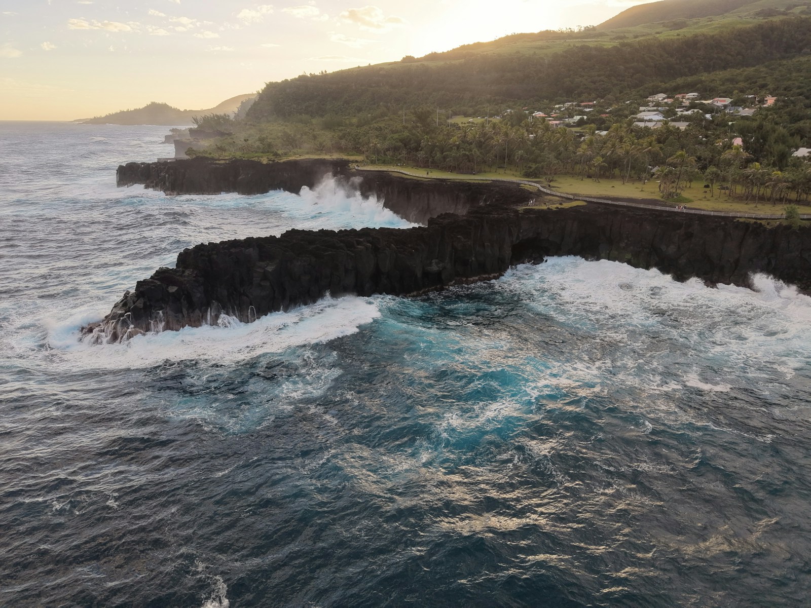The black-lava volcanic coast with crashing surf at sunset, Reunion