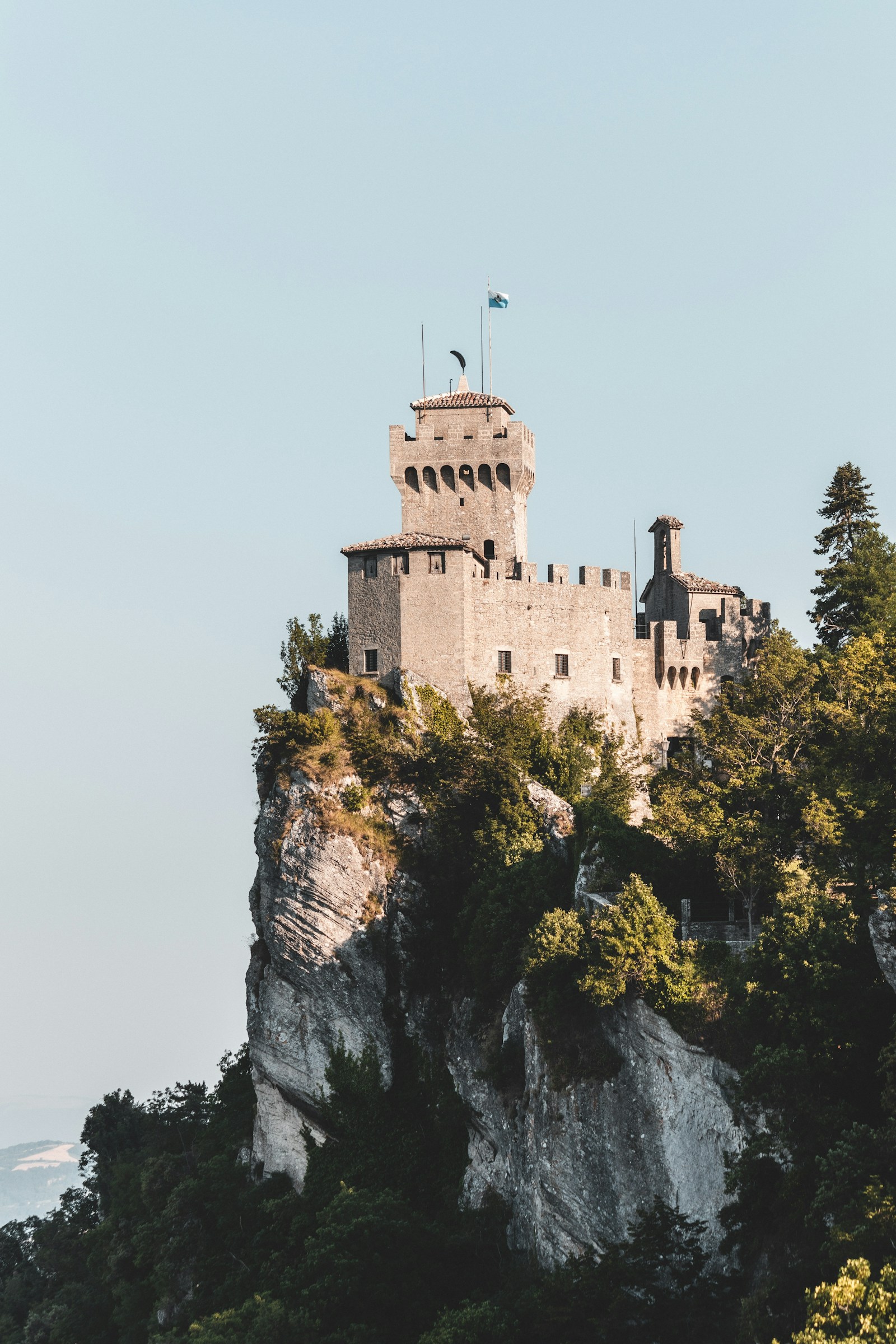 A tower of San Marino with the flag on its rocky crag on Monte Titano