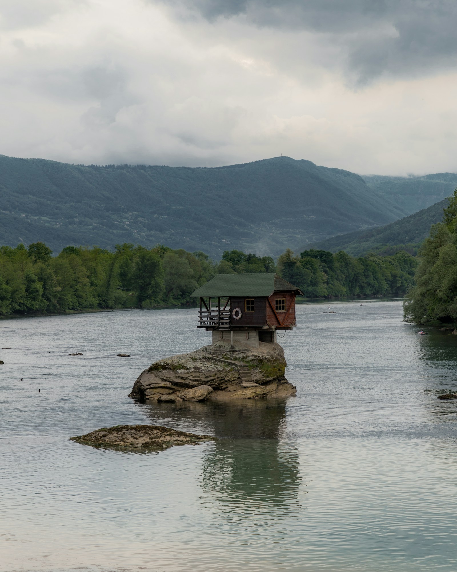 The little house on a rock in the middle of the Drina river below forested mountains in Serbia