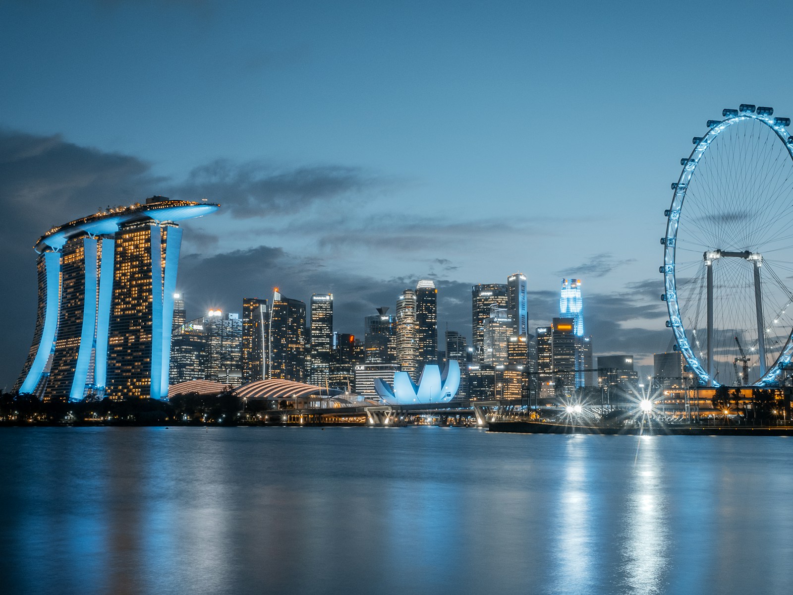 The Marina Bay Sands towers and Singapore Flyer reflected in the bay at dusk