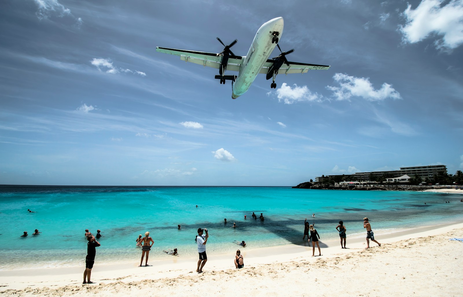A plane descending low over Maho Beach and turquoise water, Sint Maarten