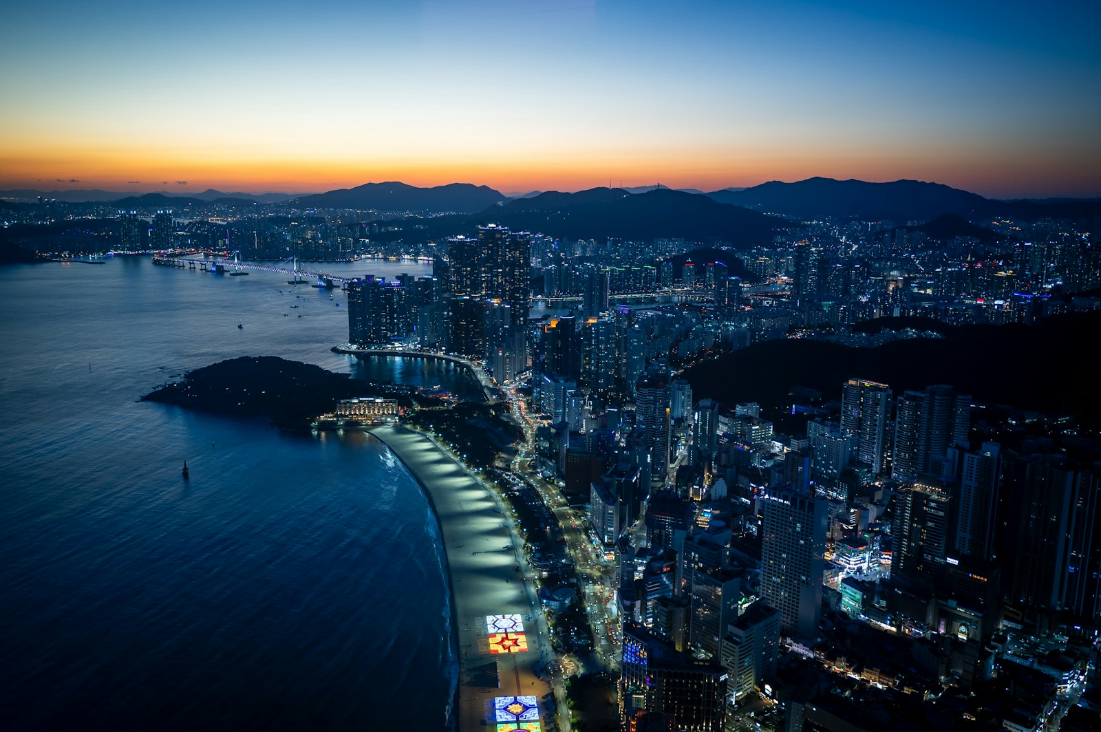 Busan at dusk, the Haeundae and Gwangalli coast lit up with the Gwangan Bridge beyond