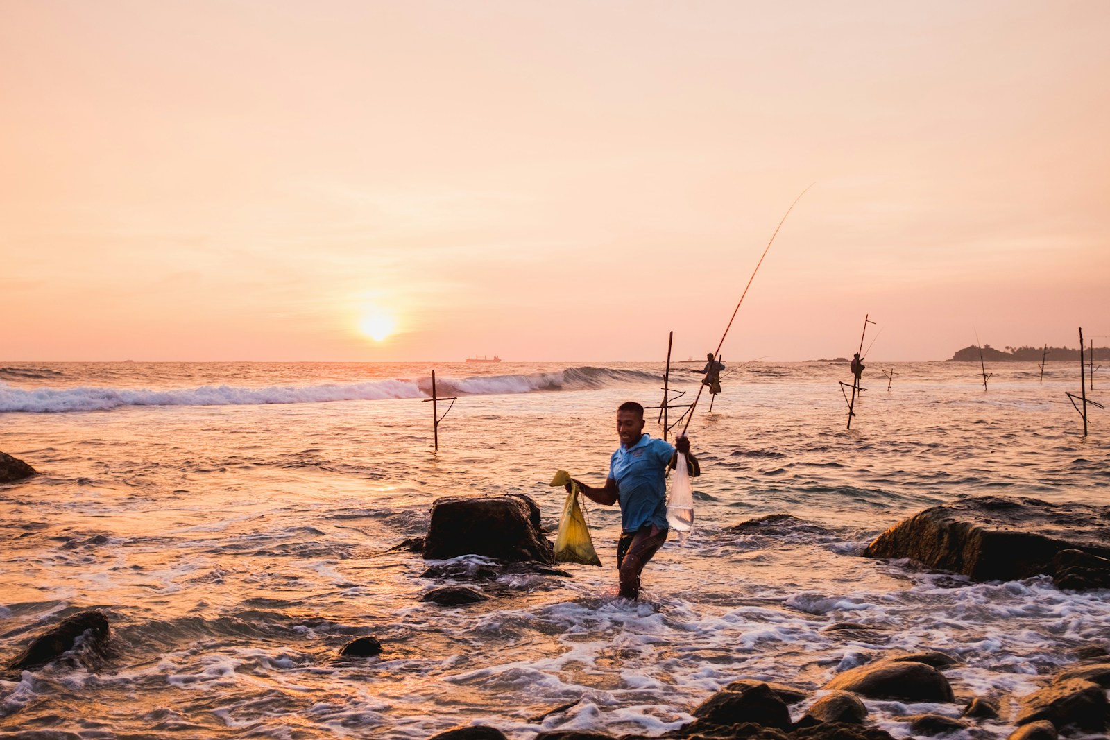 Stilt fishermen in the surf at sunset on the south coast of Sri Lanka
