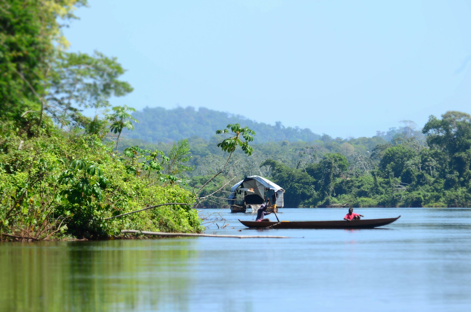 A dugout canoe on a wide jungle river in the Suriname interior